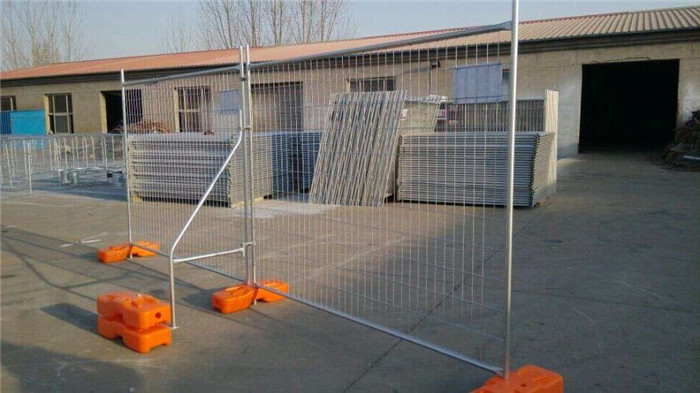 galvanized temporary fence panels with plastic feet , bracing and clamps installed on house site